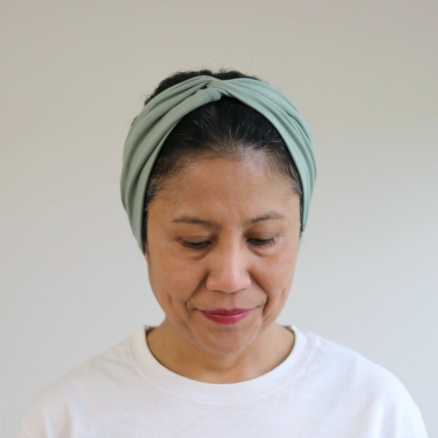 Woman wearing a green headband against a plain background