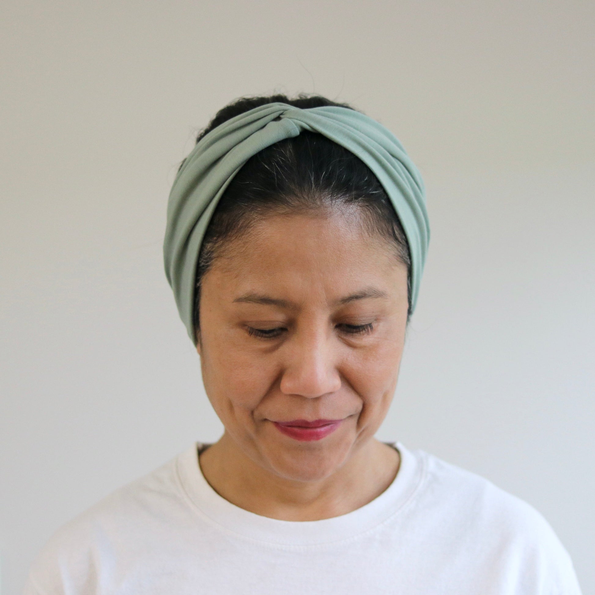 Woman wearing a green headband against a plain background