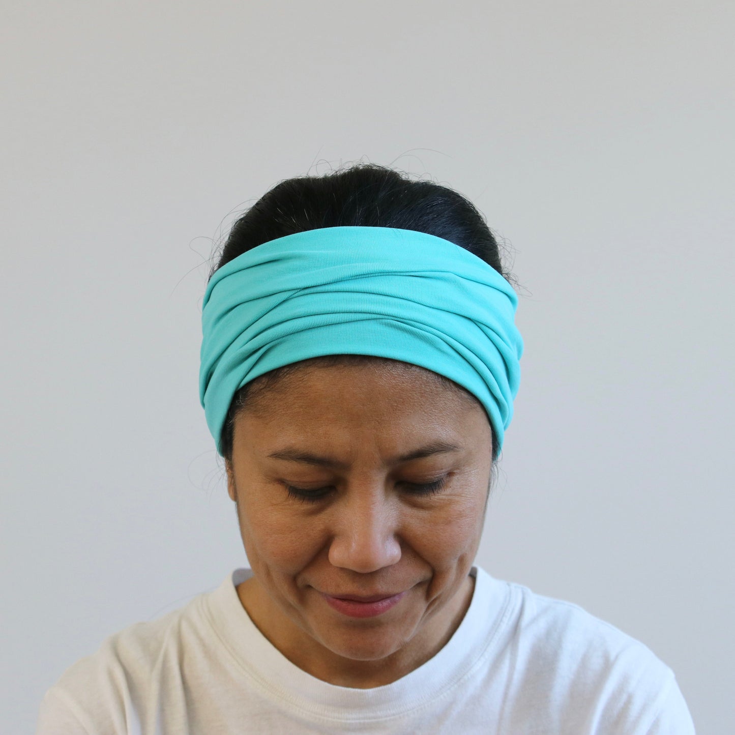 Person wearing a mint green  headband against a plain background