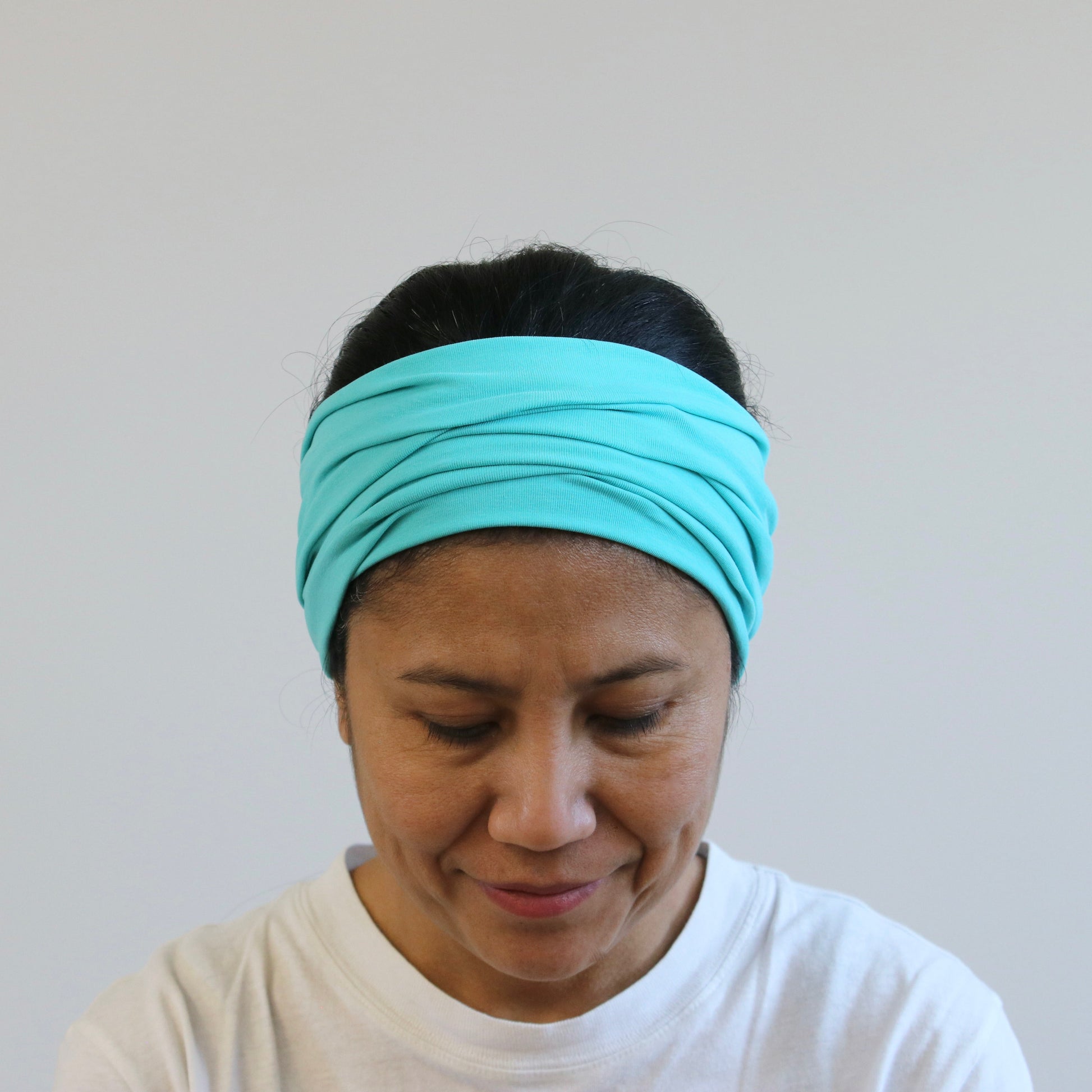 Person wearing a mint green  headband against a plain background
