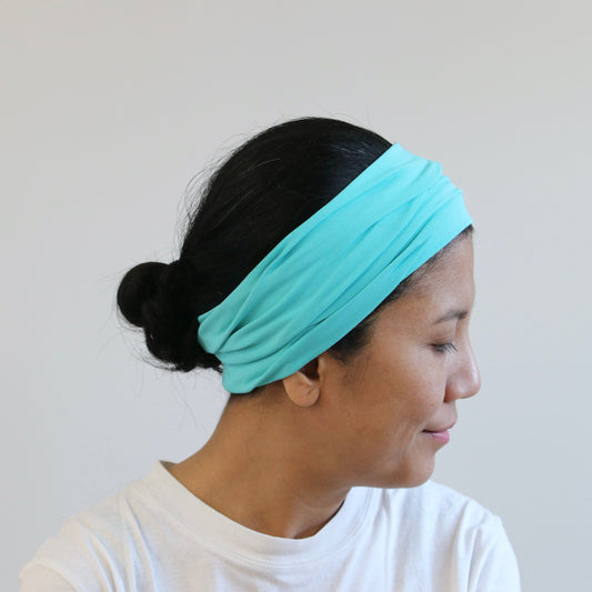 Woman wearing a mint headband against a plain background