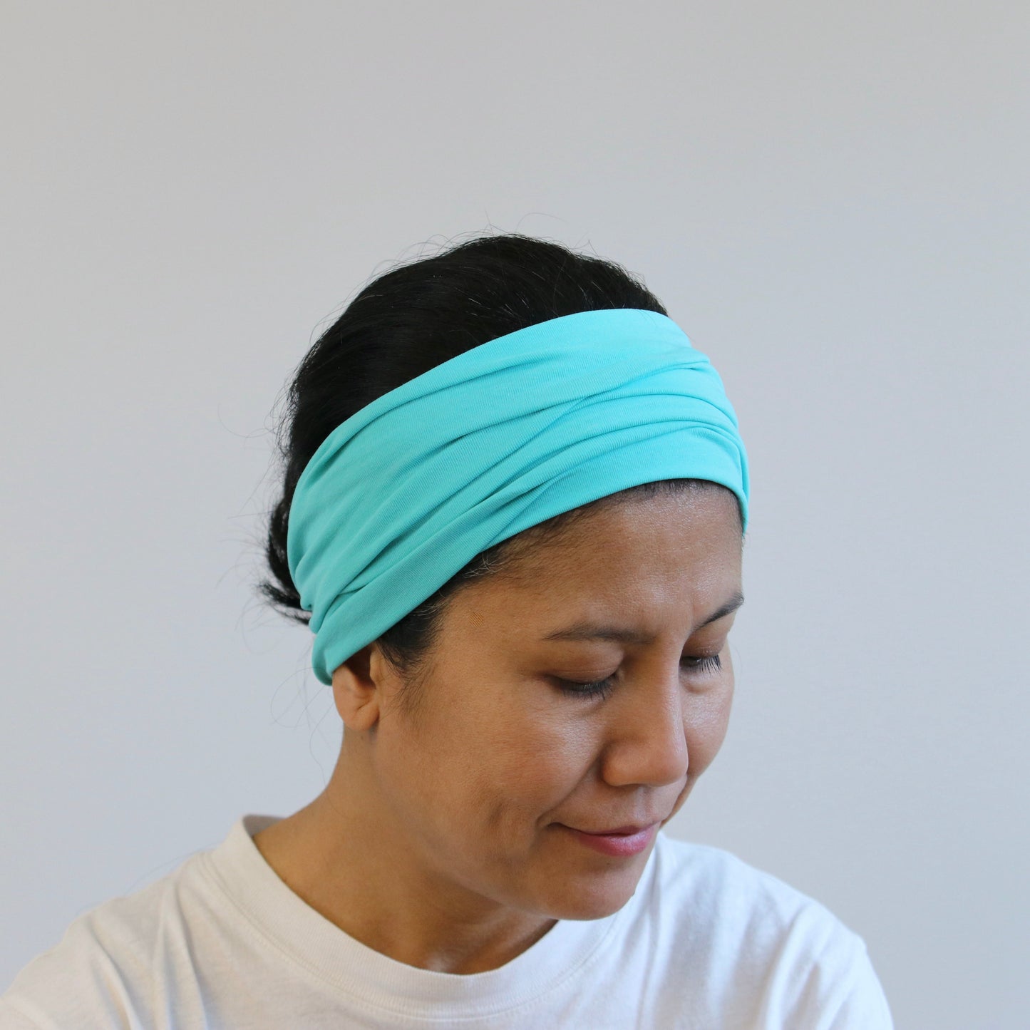 Woman wearing a mint headband against a plain background