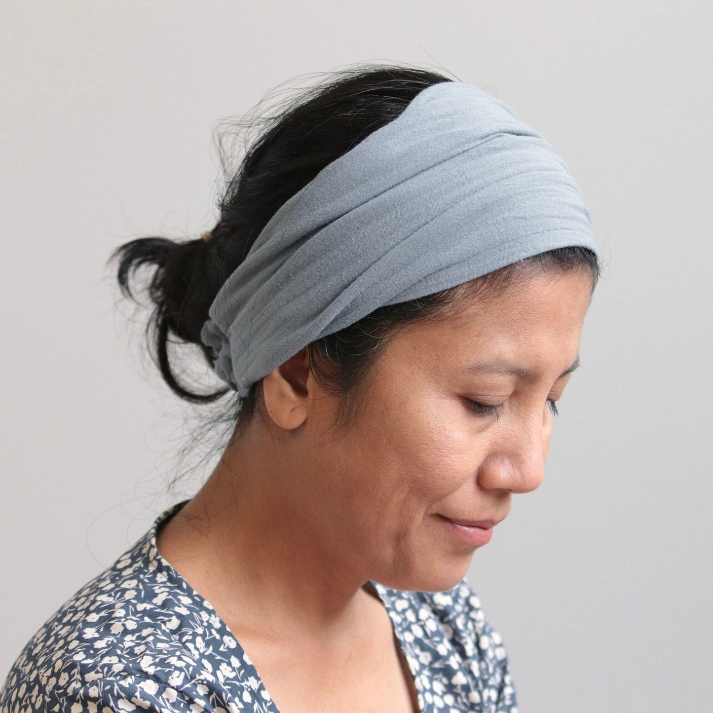 Woman wearing a light blue headband against a plain background