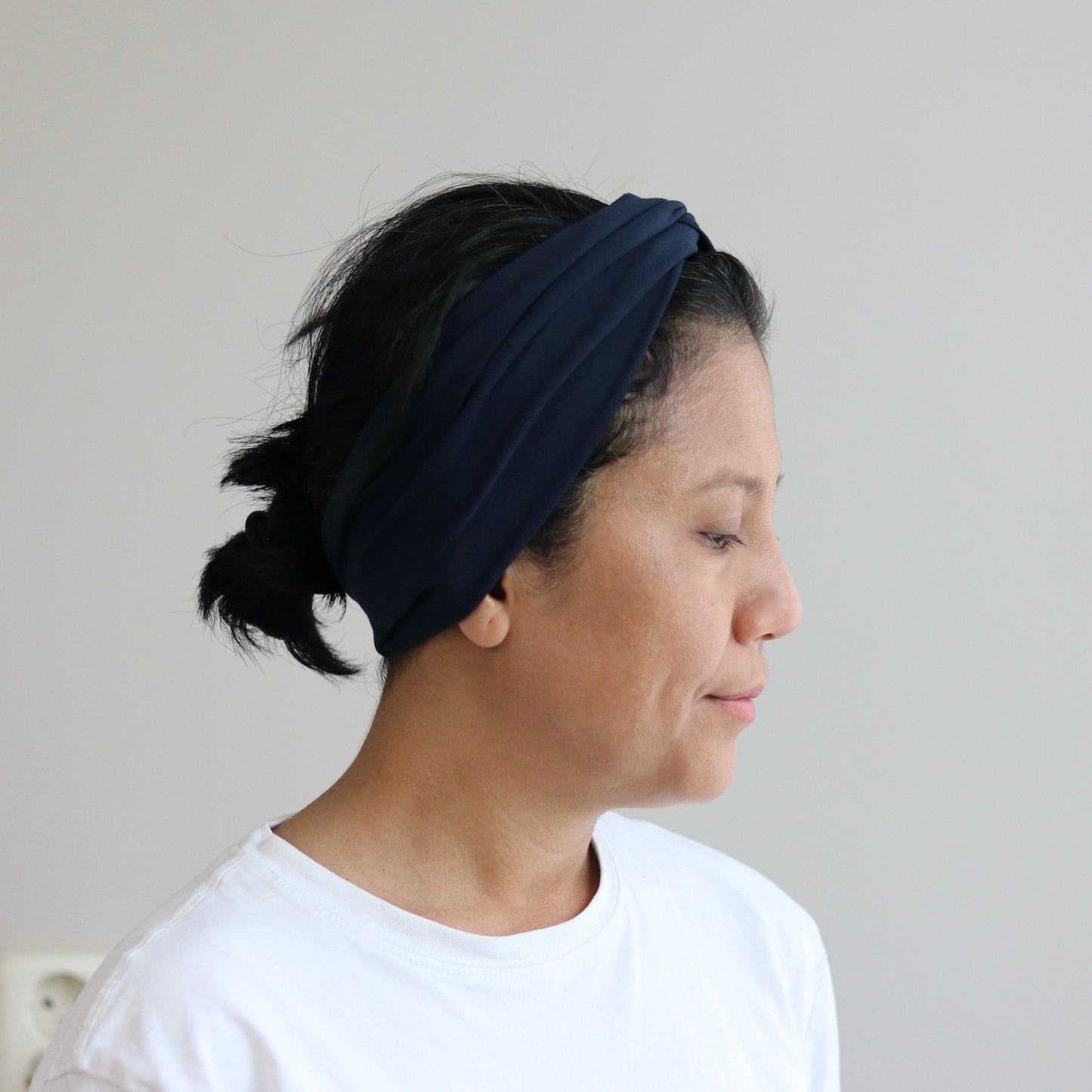 Woman wearing a dark blue headband against a plain background