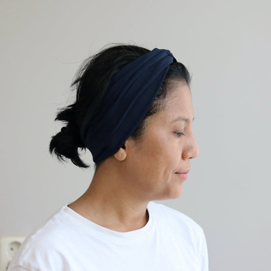 Woman wearing a dark blue headband against a plain background