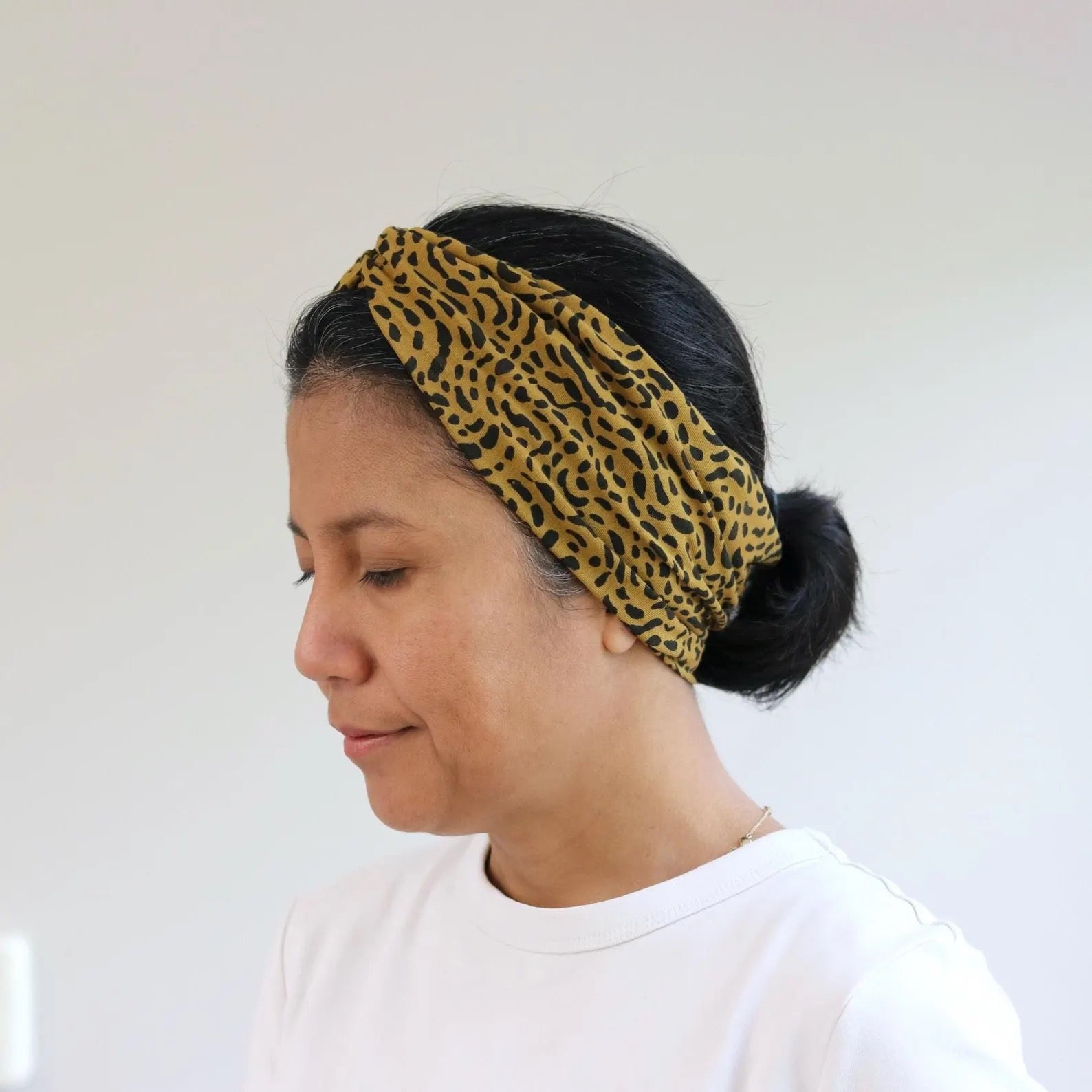 Person wearing a leopard print headband against a white background