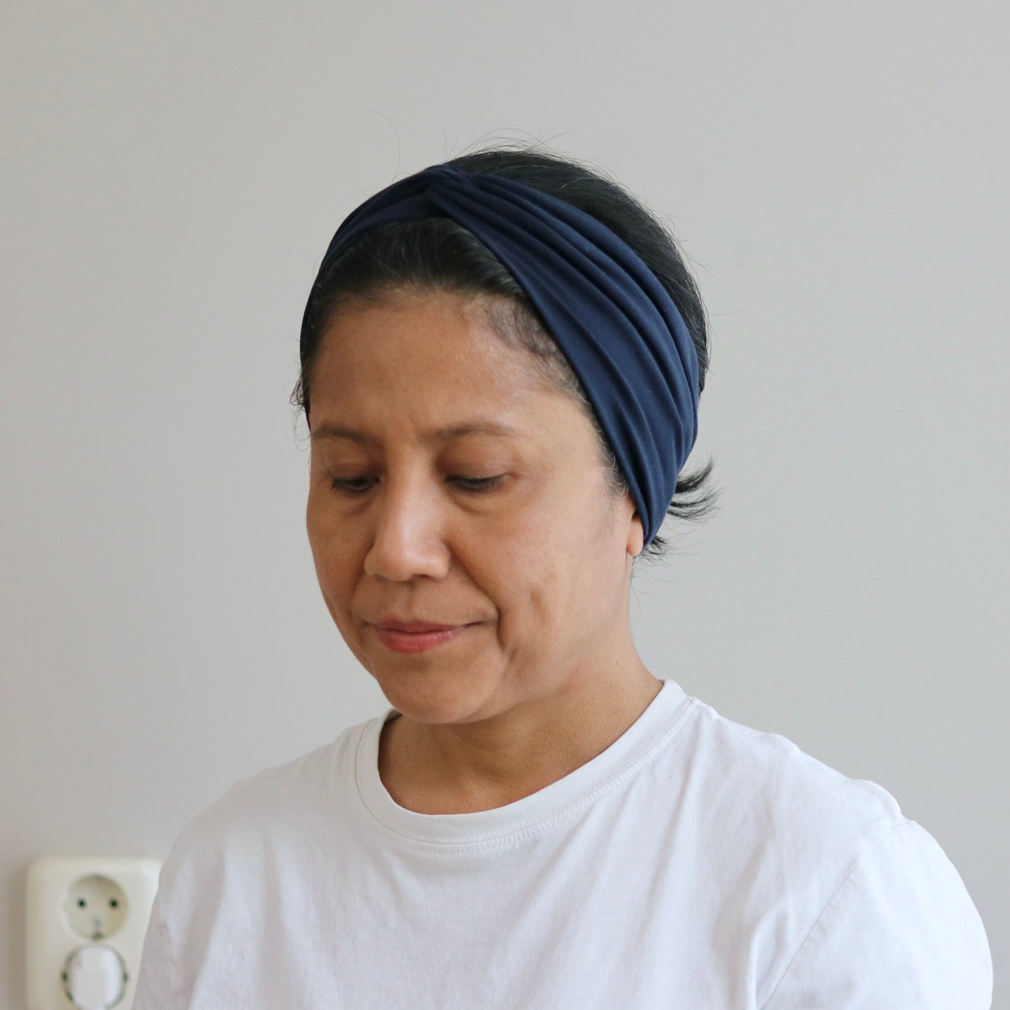 Woman wearing a blue headband against a plain background