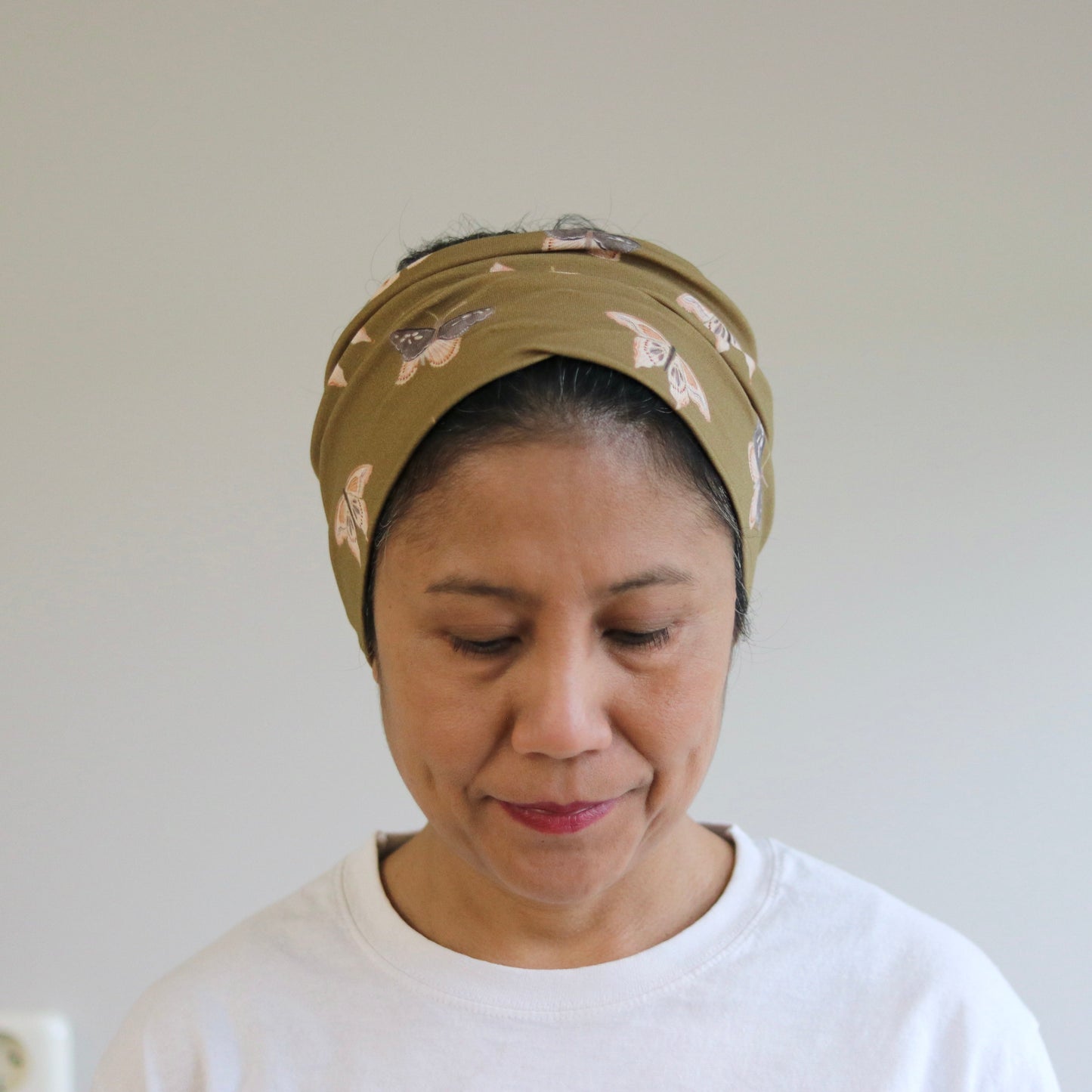 Woman wearing a butterflies patterned headband against a plain background
