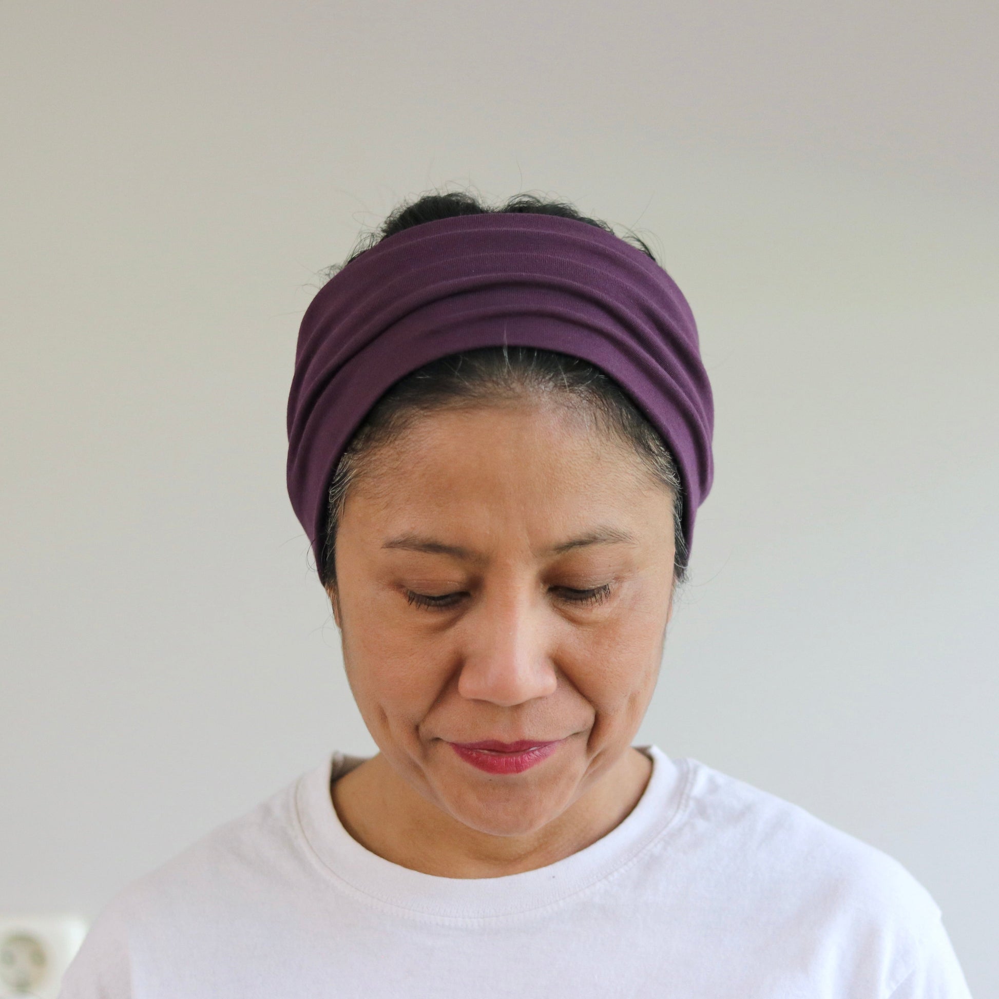 Woman wearing a purple headband against a plain background