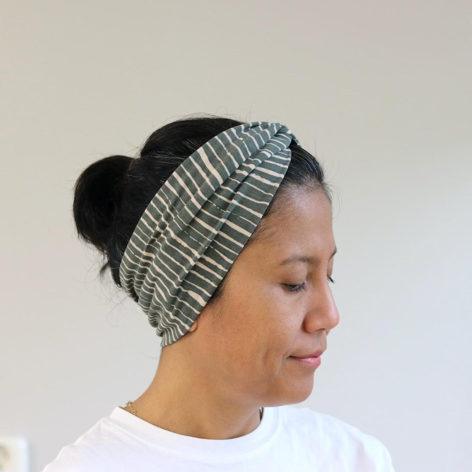 Woman wearing a striped headband against a plain background