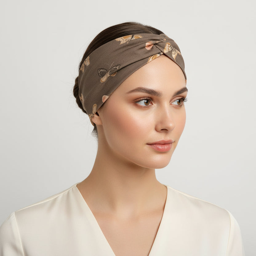 Woman wearing a brown patterned headscarf on a plain background