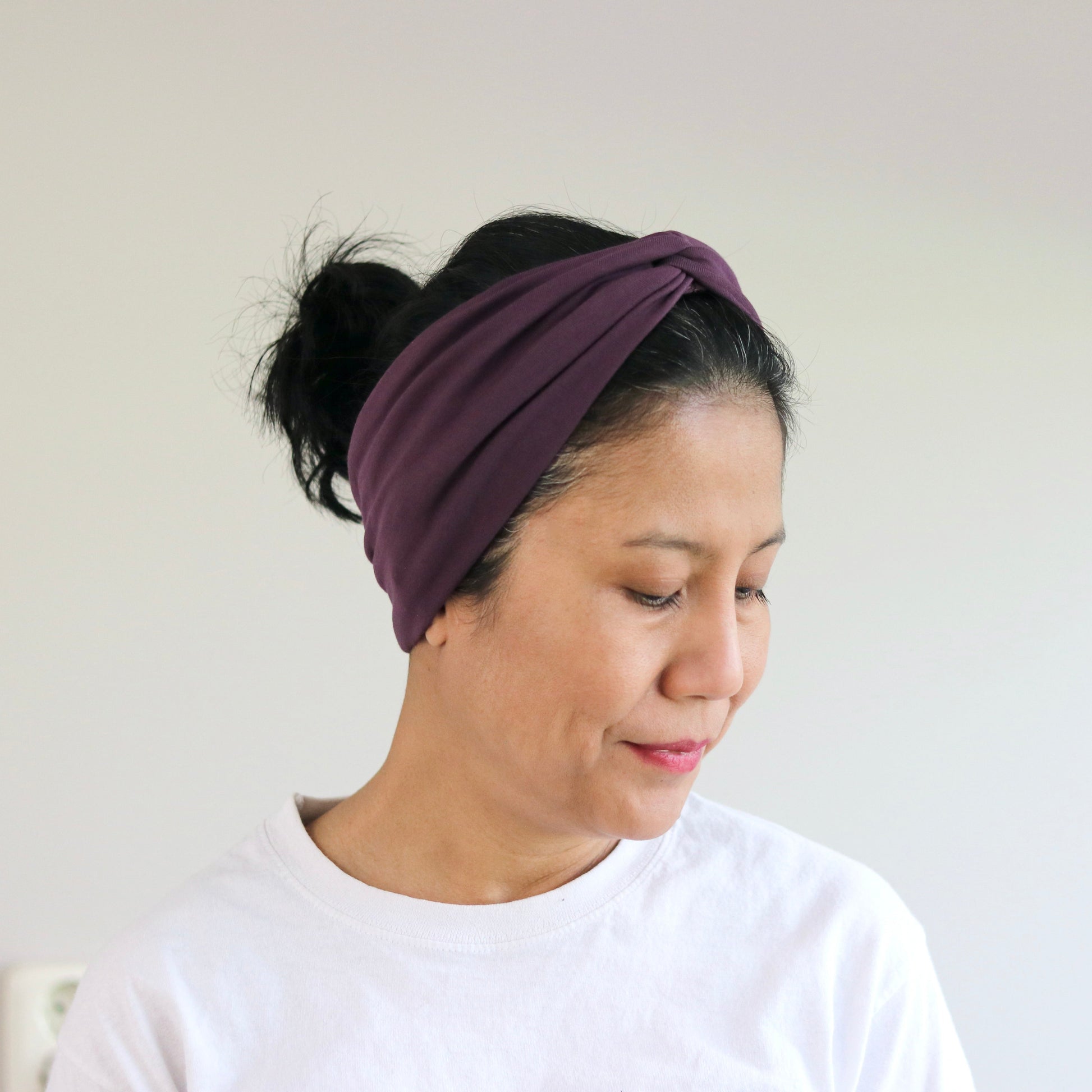 Woman wearing a purple headband against a plain background