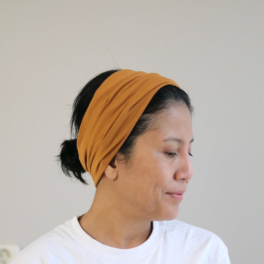 Woman wearing a cooper- blush headband against a plain background