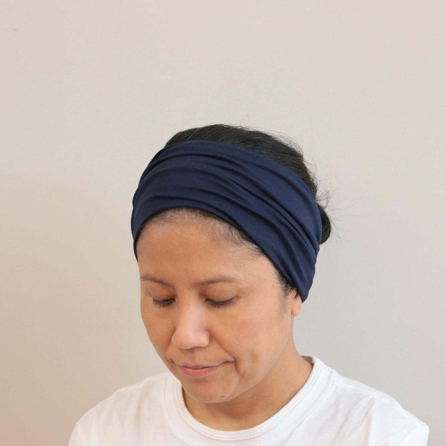 Woman wearing a navy blue headband against a plain background