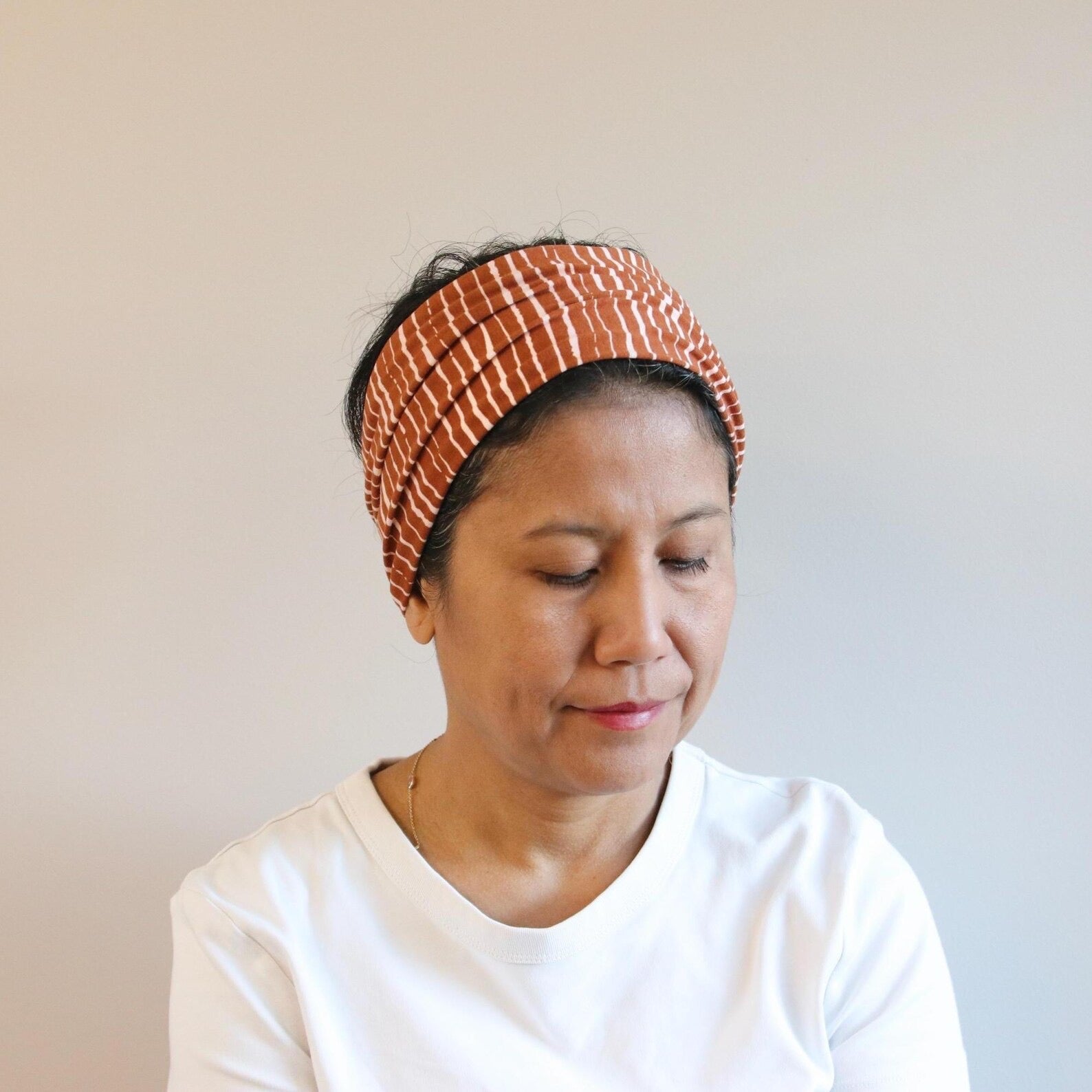 Woman wearing a patterned headband against a plain background