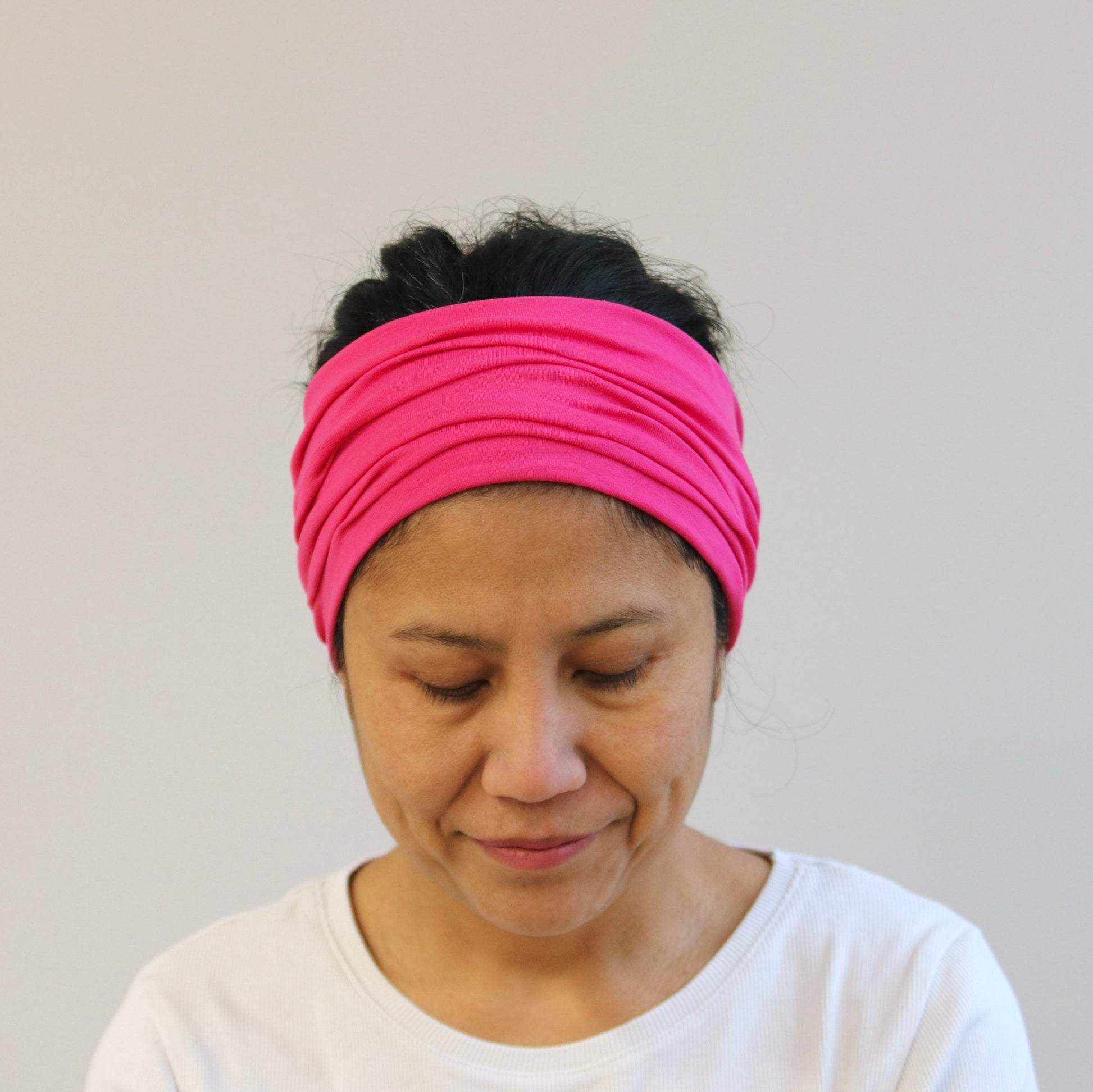 Woman wearing a pink headband against a plain background