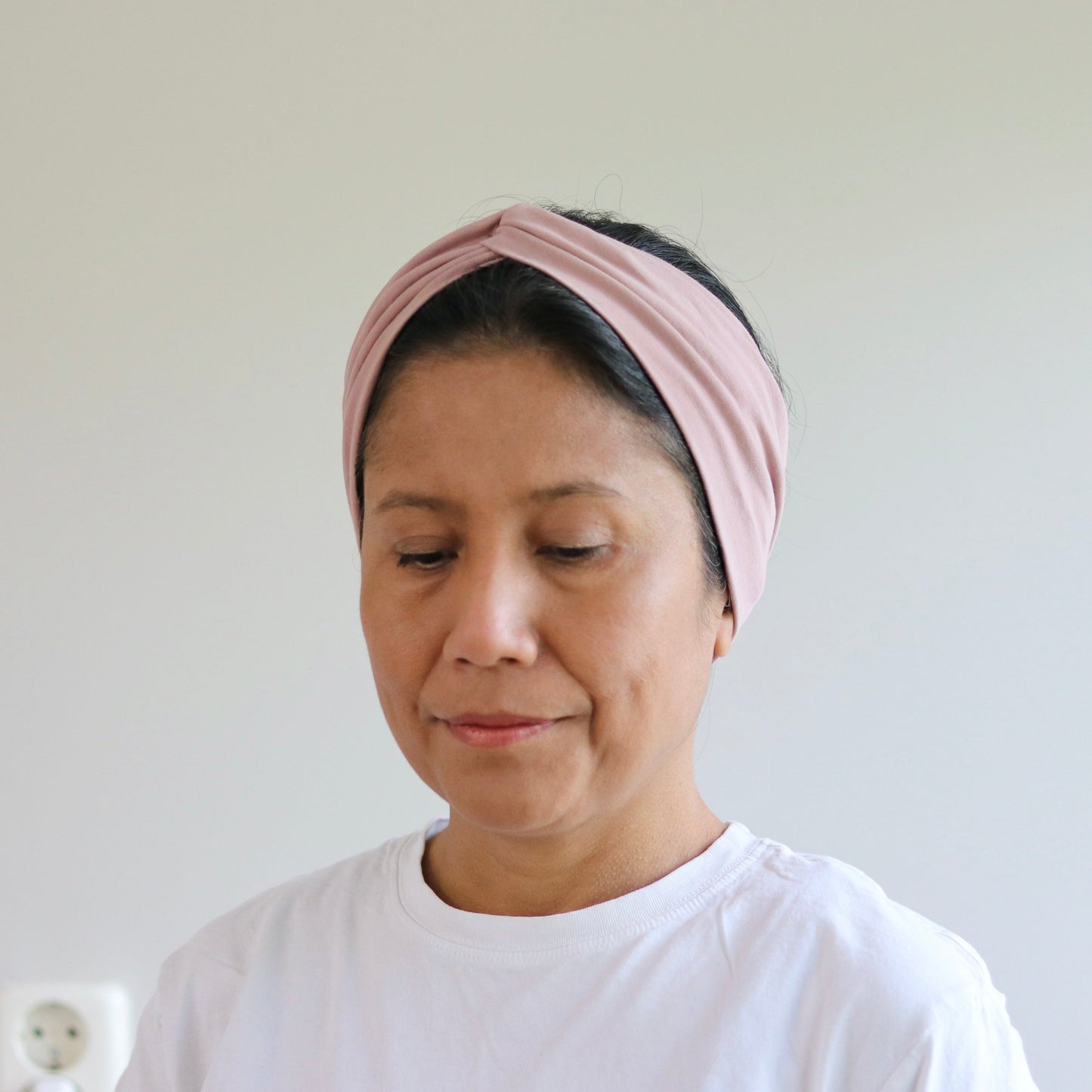 Woman wearing a pink headband against a plain background