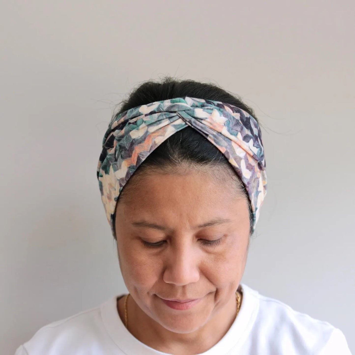 Woman wearing a patterned headband against a plain background