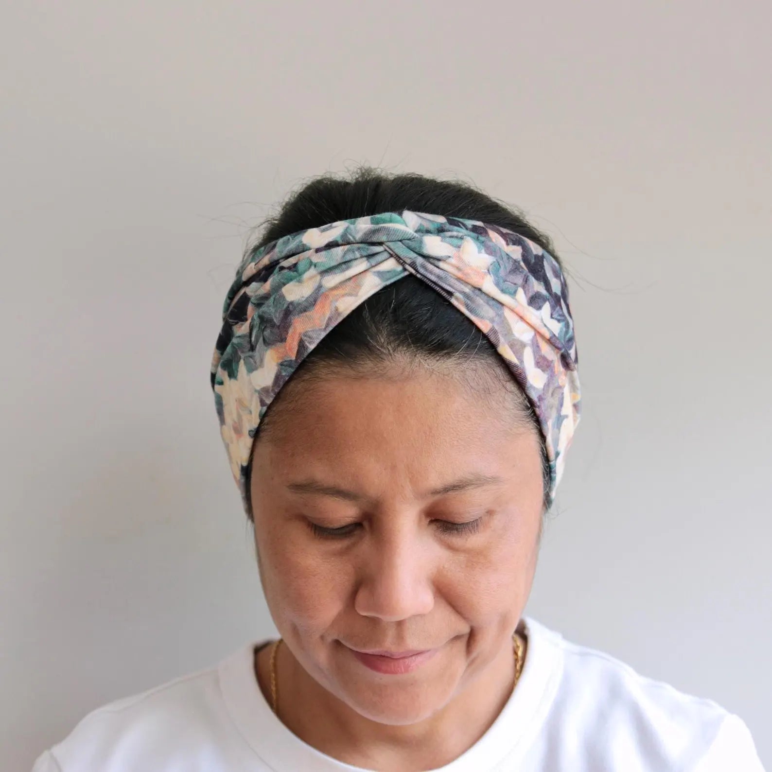 Woman wearing a patterned headband against a plain background