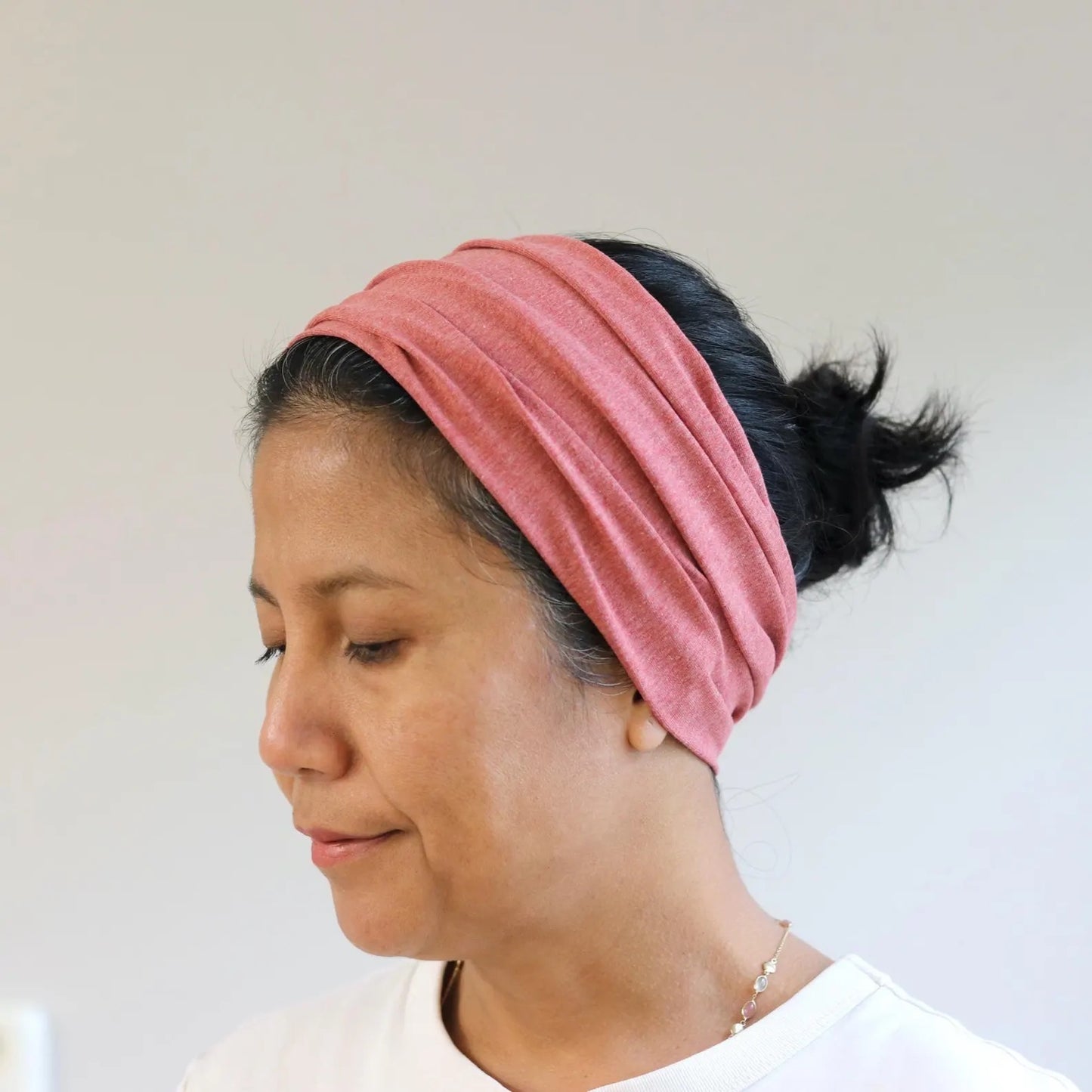 Woman wearing an earthy red- melange headband with a neutral background