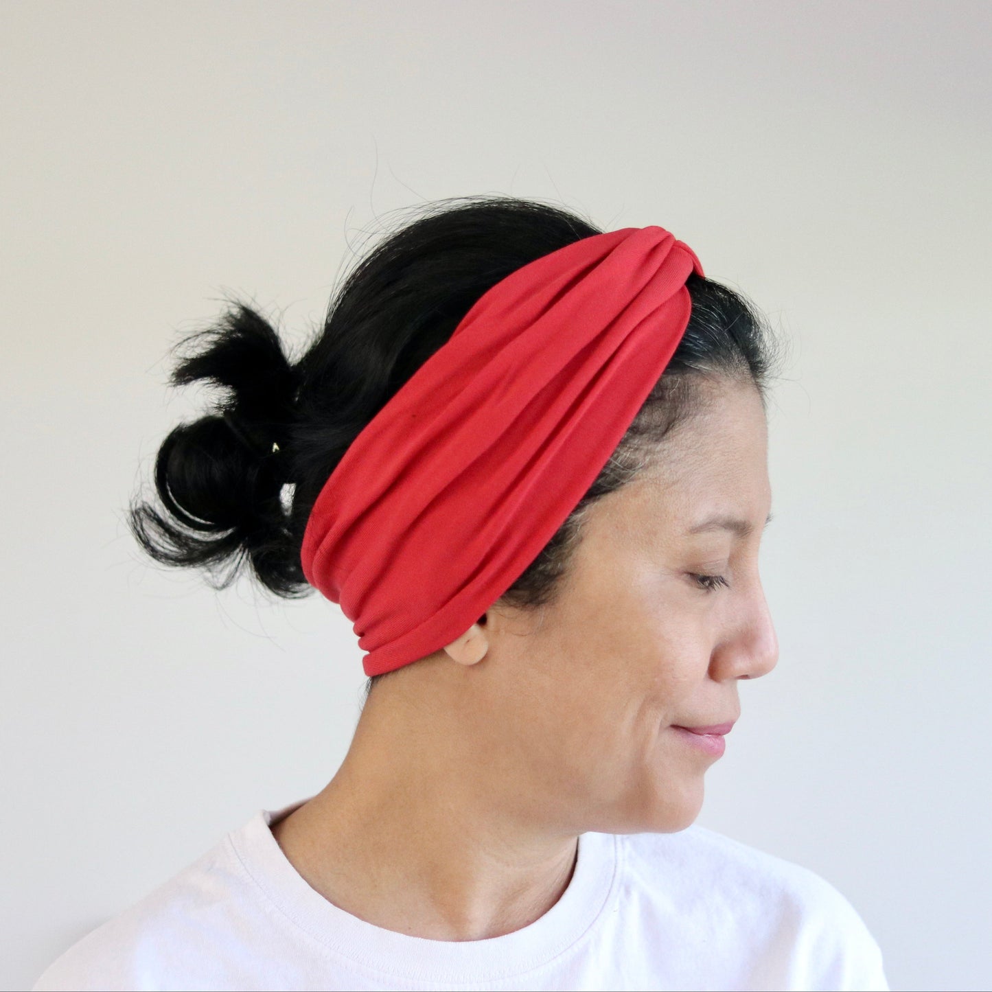 Woman wearing a red headband against a plain background