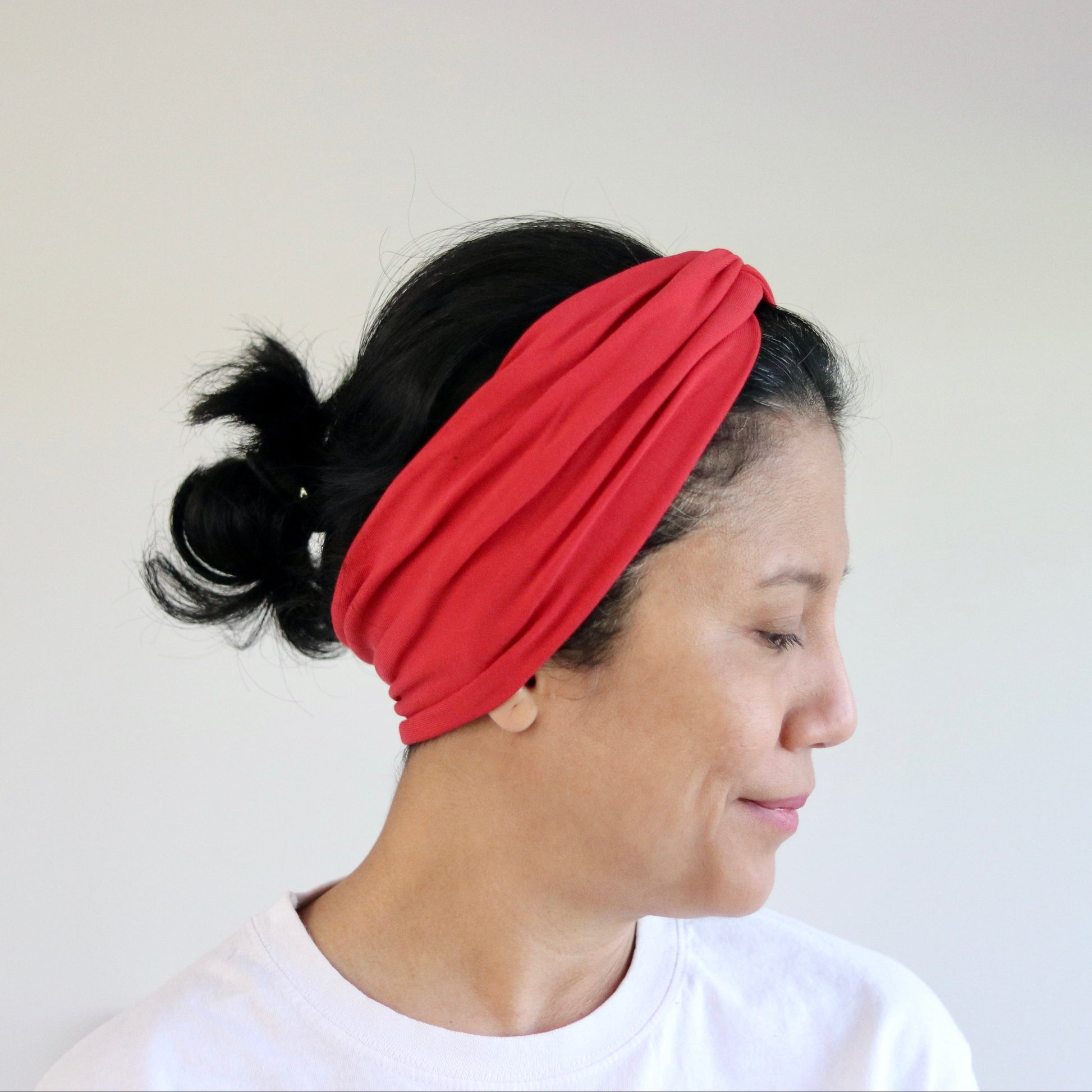 Woman wearing a red headband against a plain background