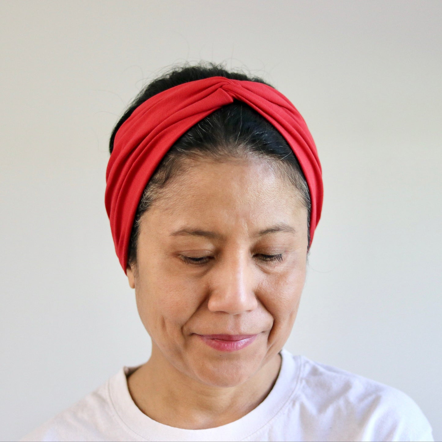 Woman wearing a red headband against a plain background