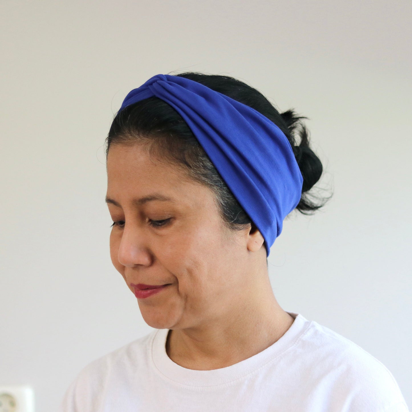 Woman wearing a blue headband against a plain background