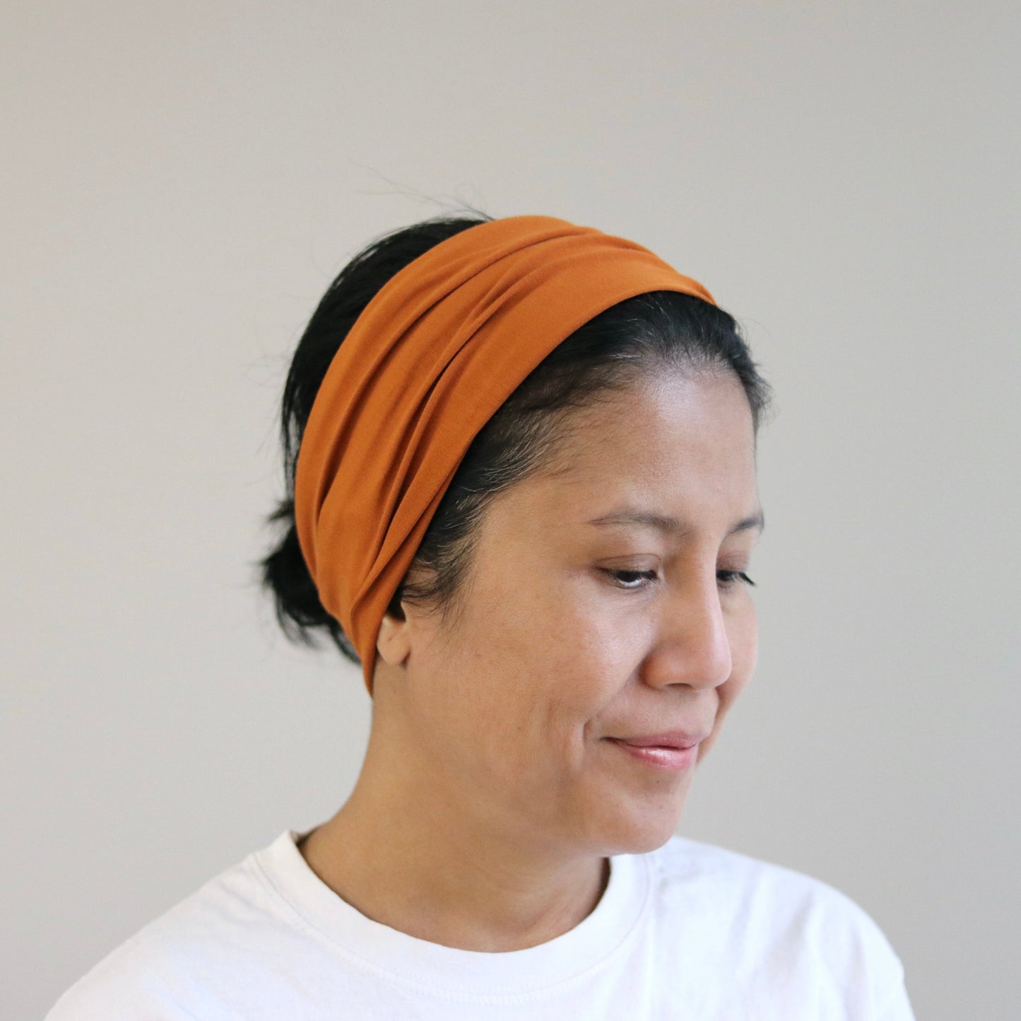 Woman wearing an orange headband against a plain background