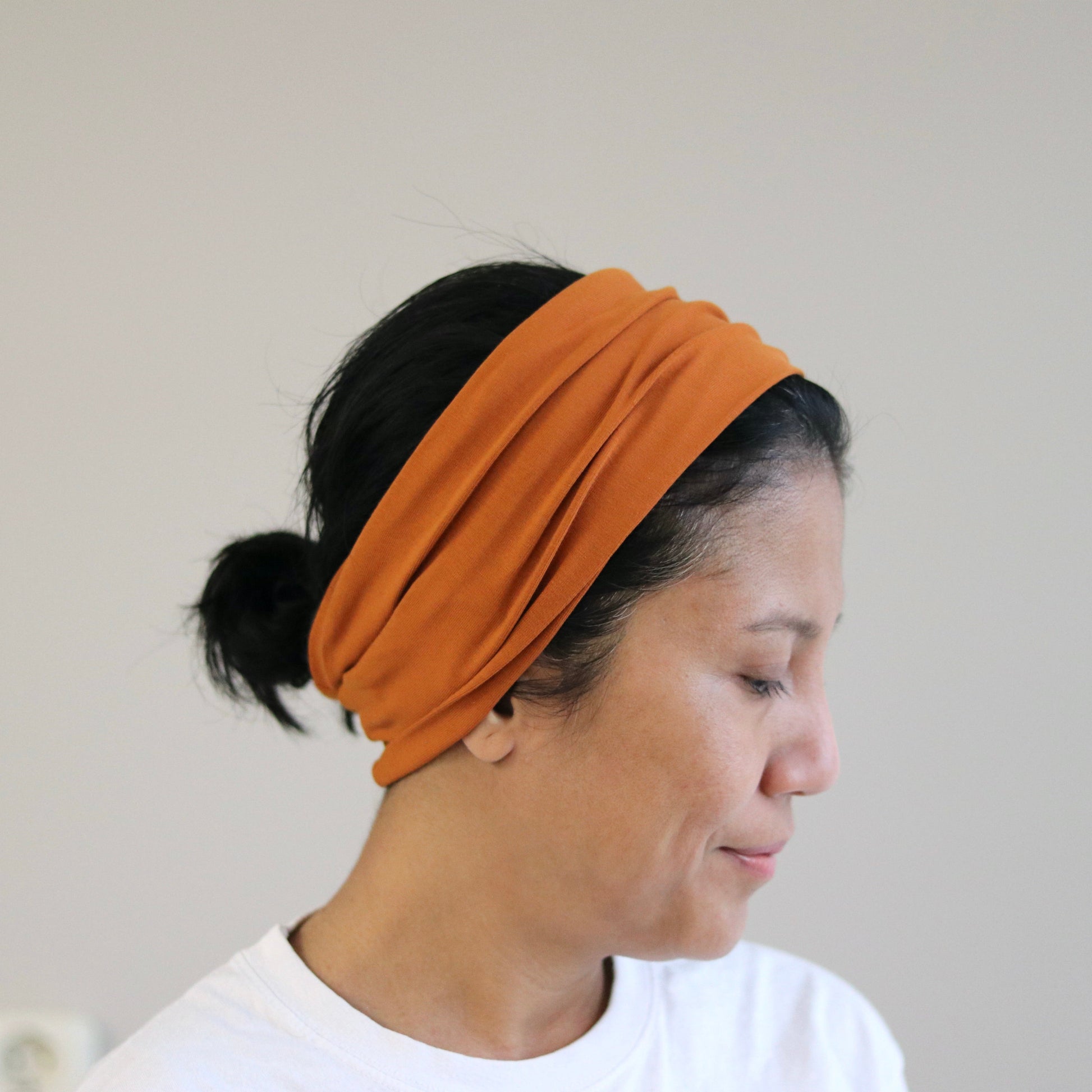 Woman wearing an orange rust headband against a plain background