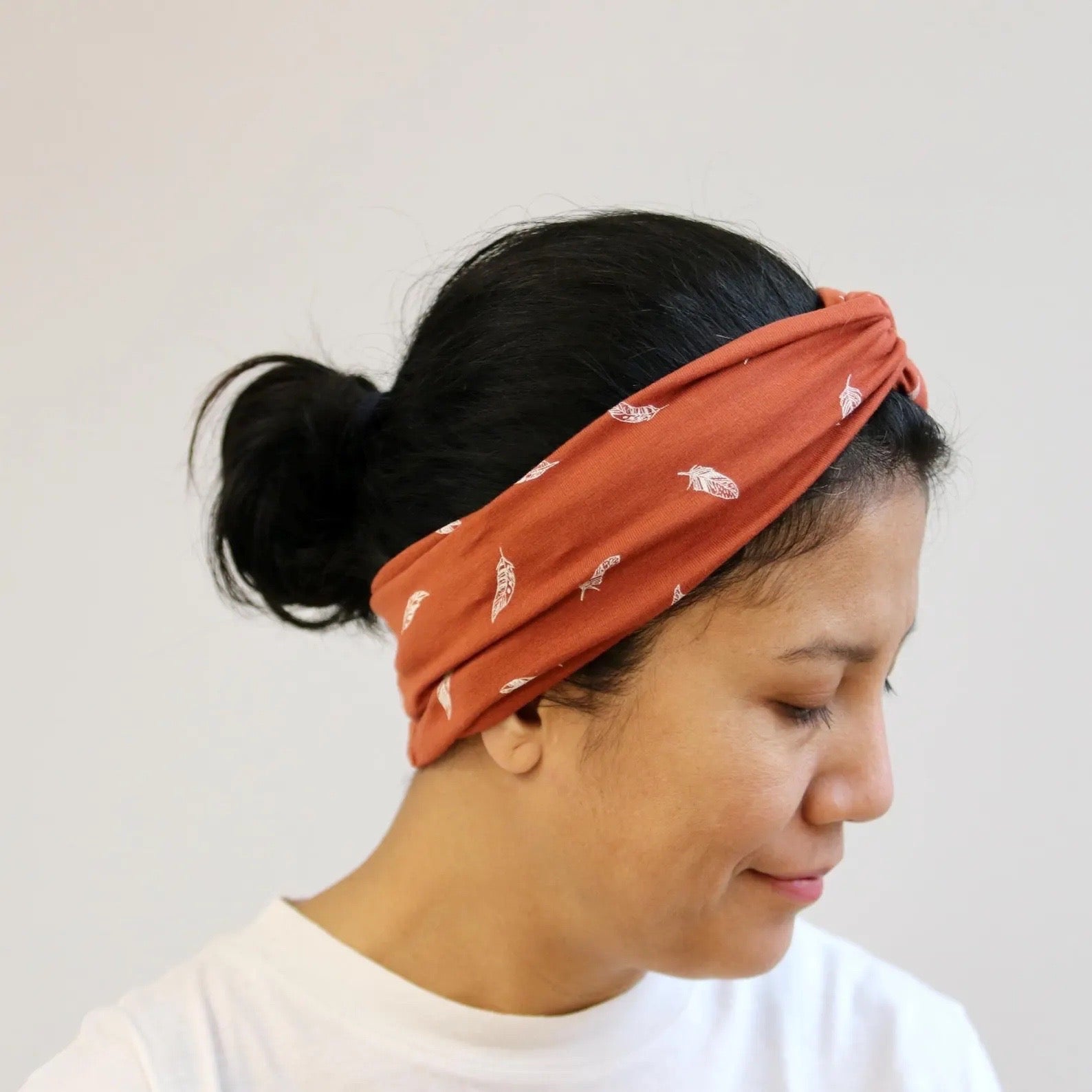 Person wearing a rust-colored headband with white patterns on a plain background