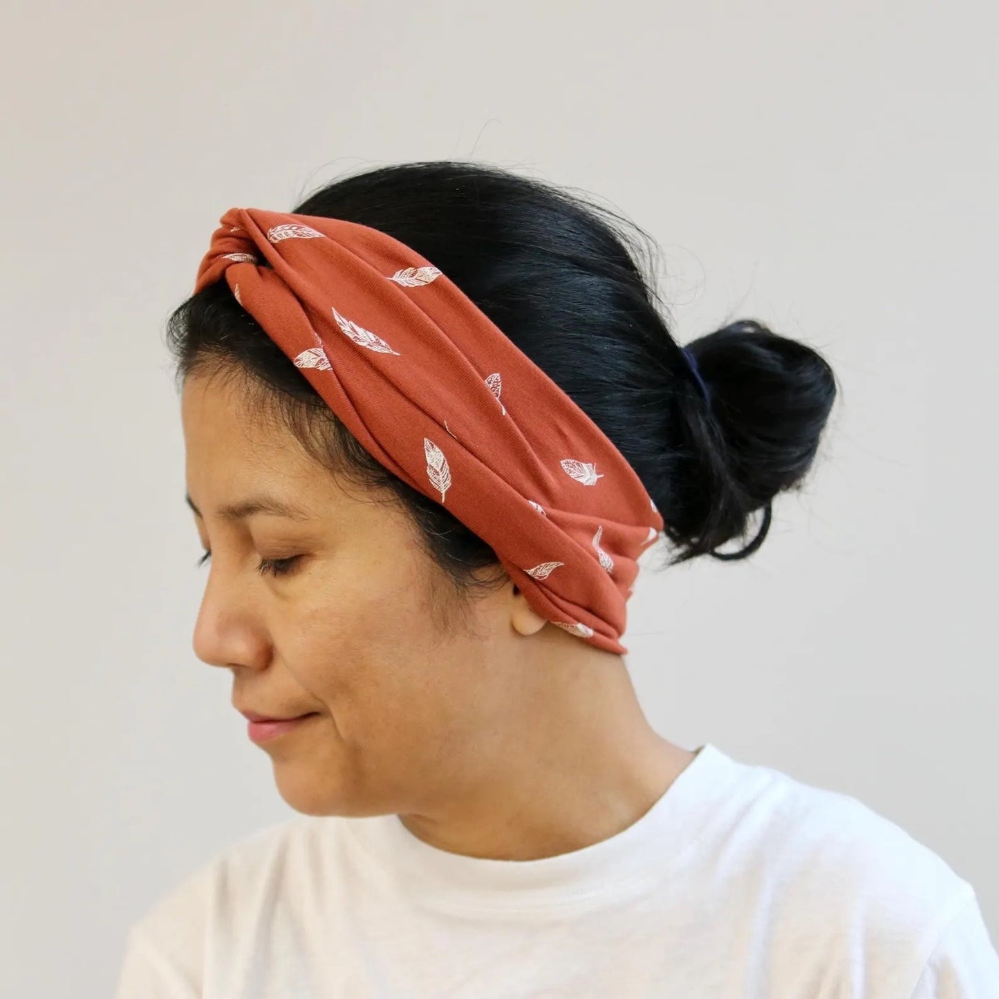 Person wearing a rust-colored headband with white patterns on a plain background