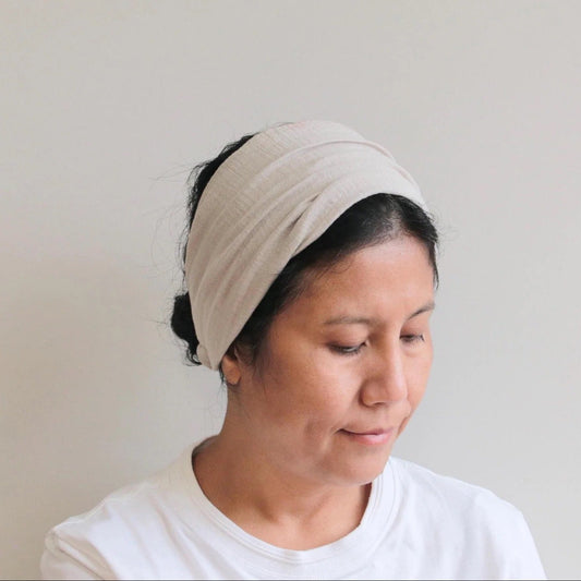 Woman wearing a beige headband against a plain background