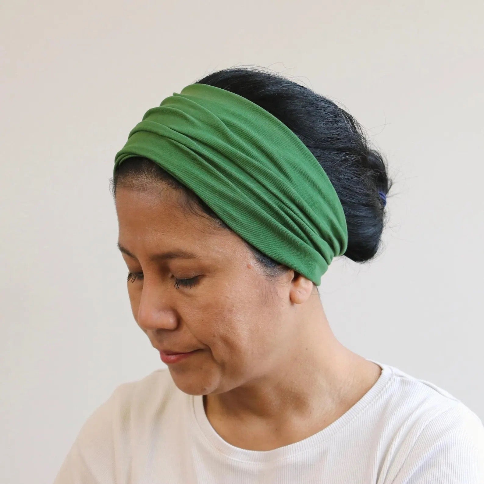 Woman wearing a green headband against a plain background