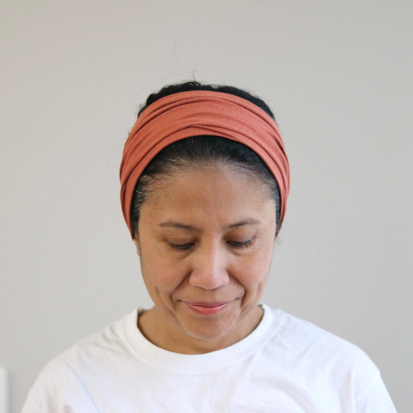 Woman wearing a terra headband against a plain background