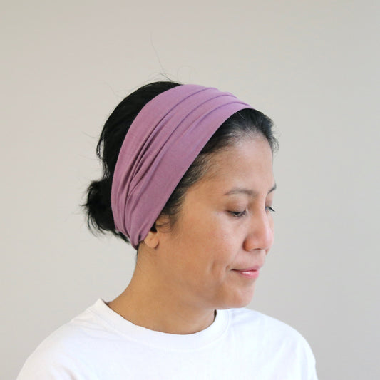 Woman wearing a purple headband against a plain background