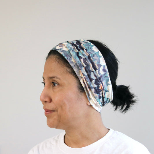 Woman wearing a patterned headband against a plain background