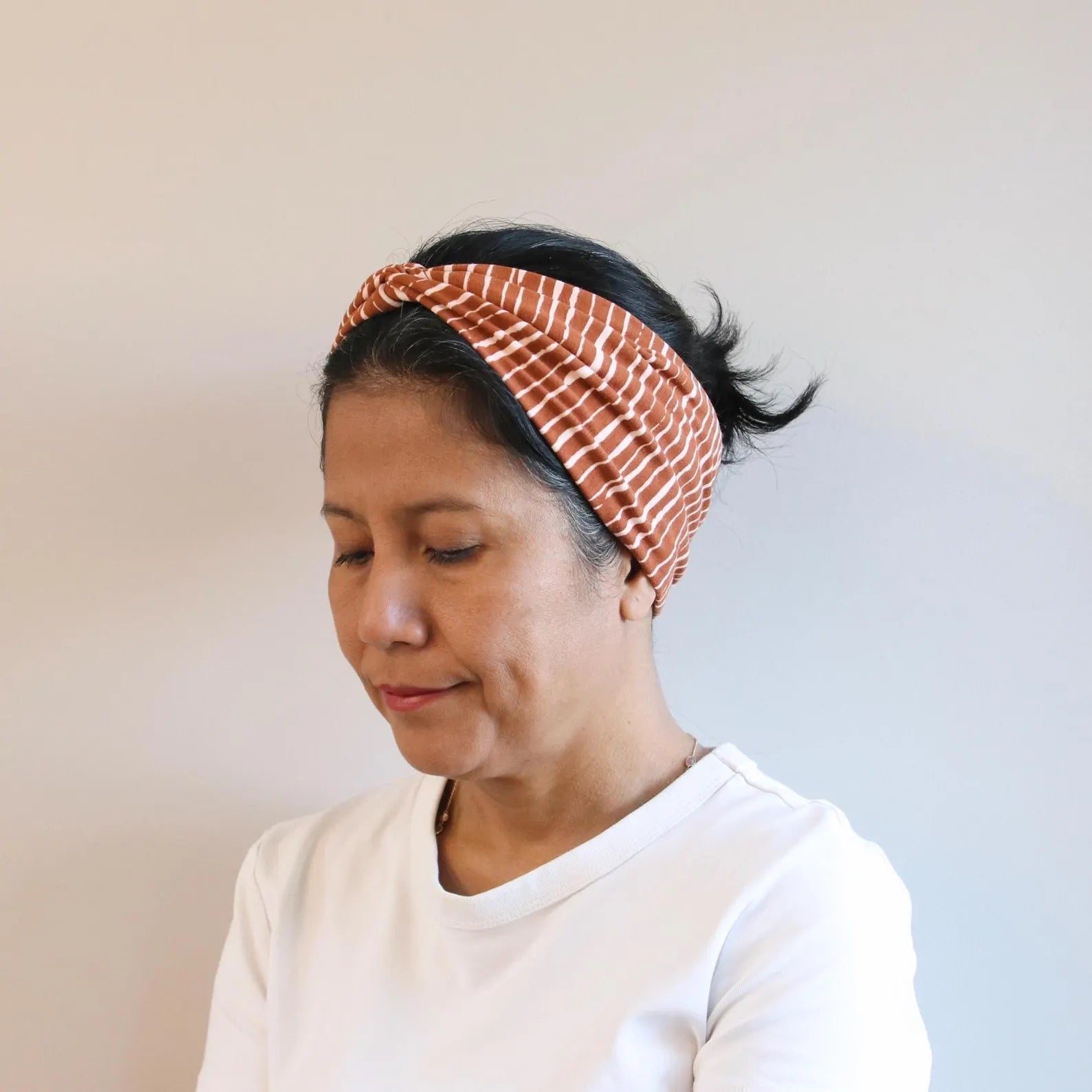 Woman wearing a patterned headband against a plain background