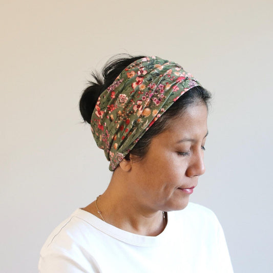 Woman wearing a floral headband against a plain background