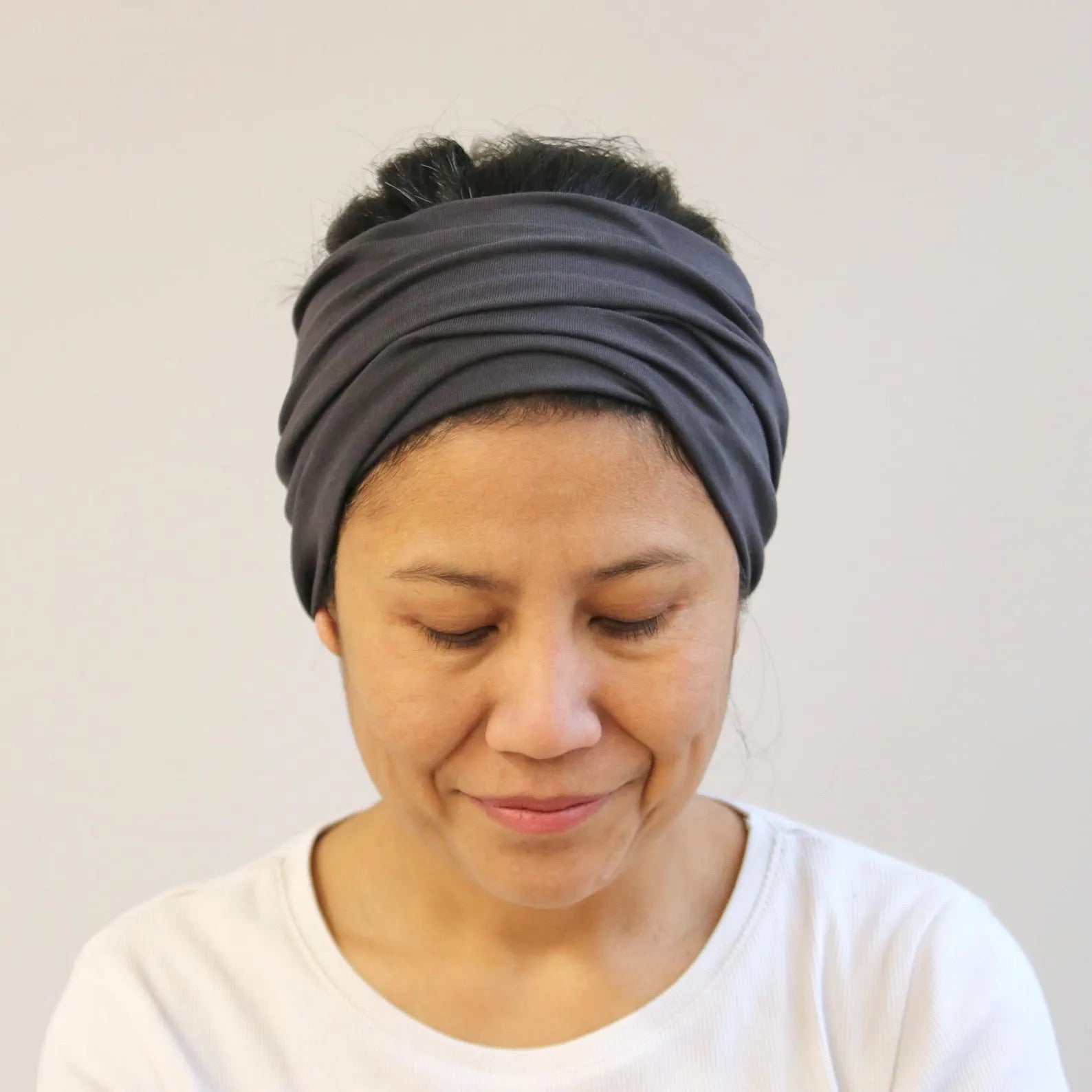 Woman wearing a gray headscarf against a plain background