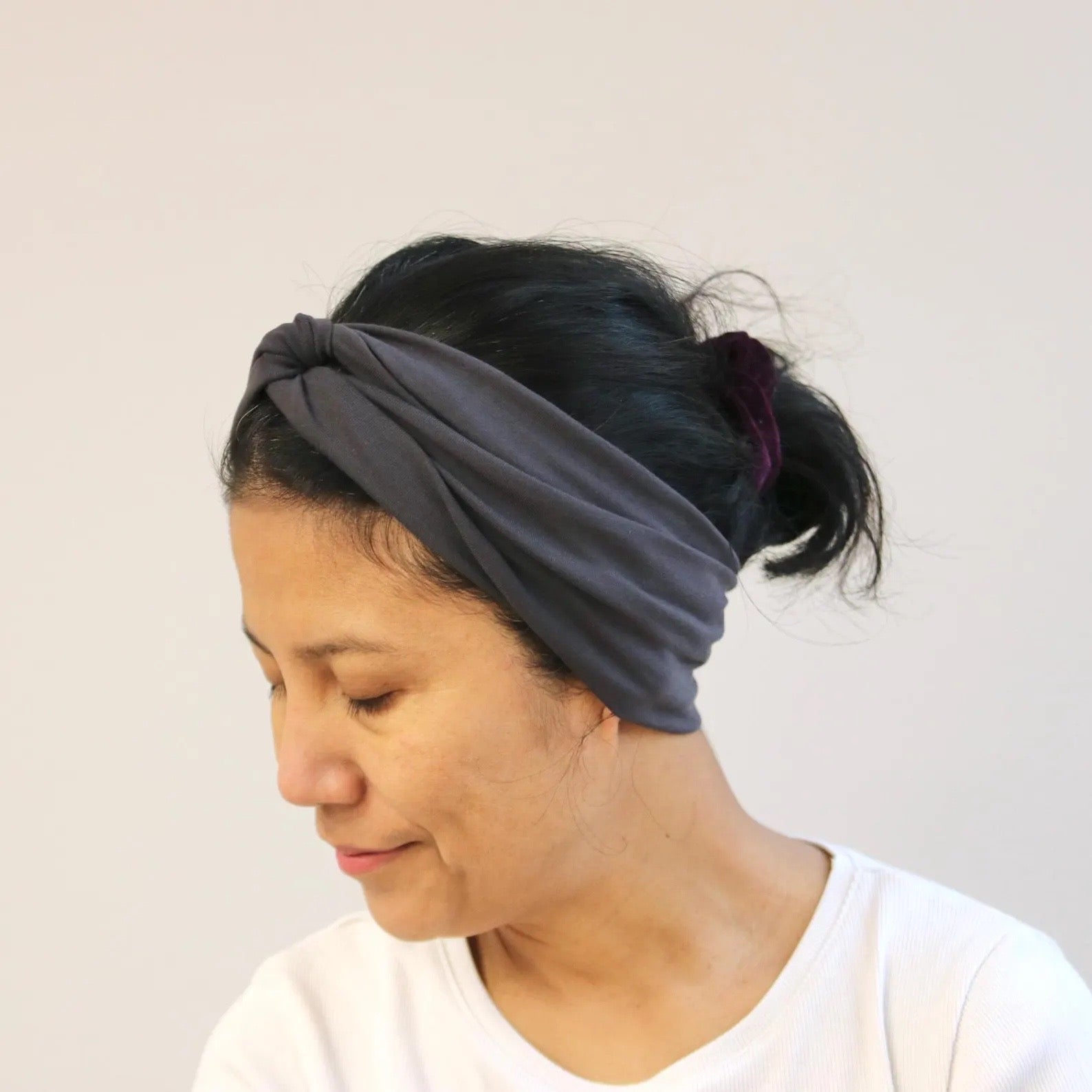 Woman wearing a gray headband against a plain background