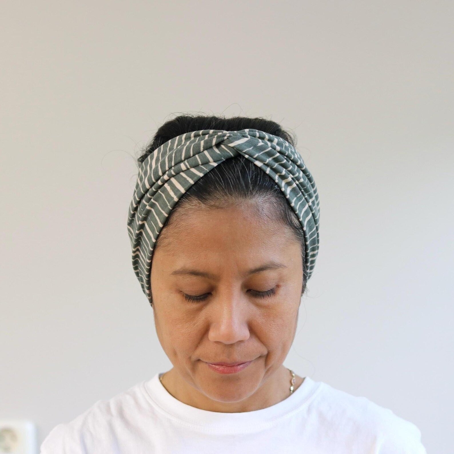 Woman wearing a green patterned headscarf against a plain background
