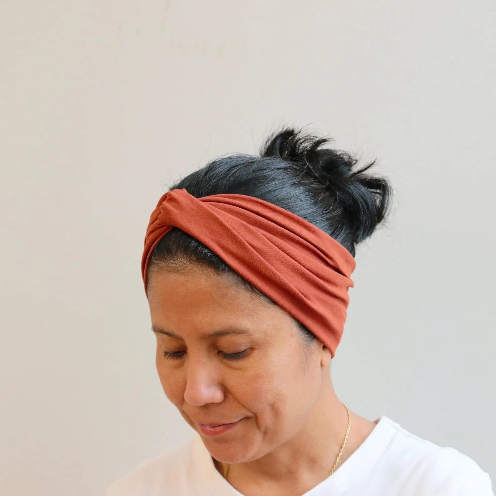 Woman wearing a rust-colored headband against a plain background