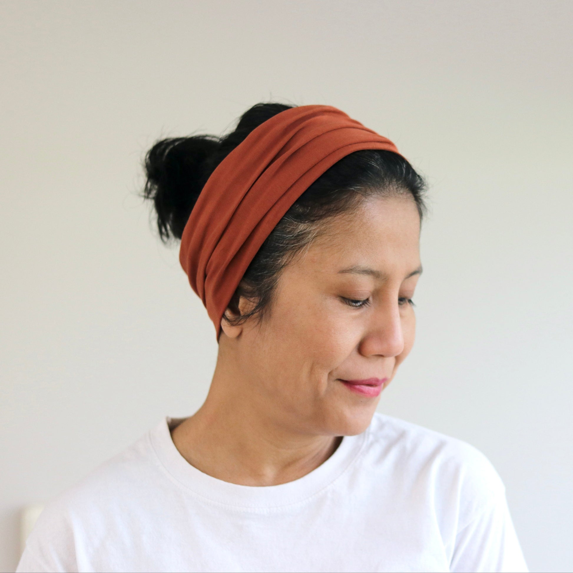 Woman wearing a rust-colored headband against a plain background