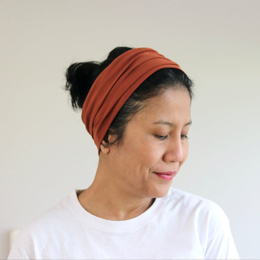 Woman wearing a rust-colored headband against a plain background