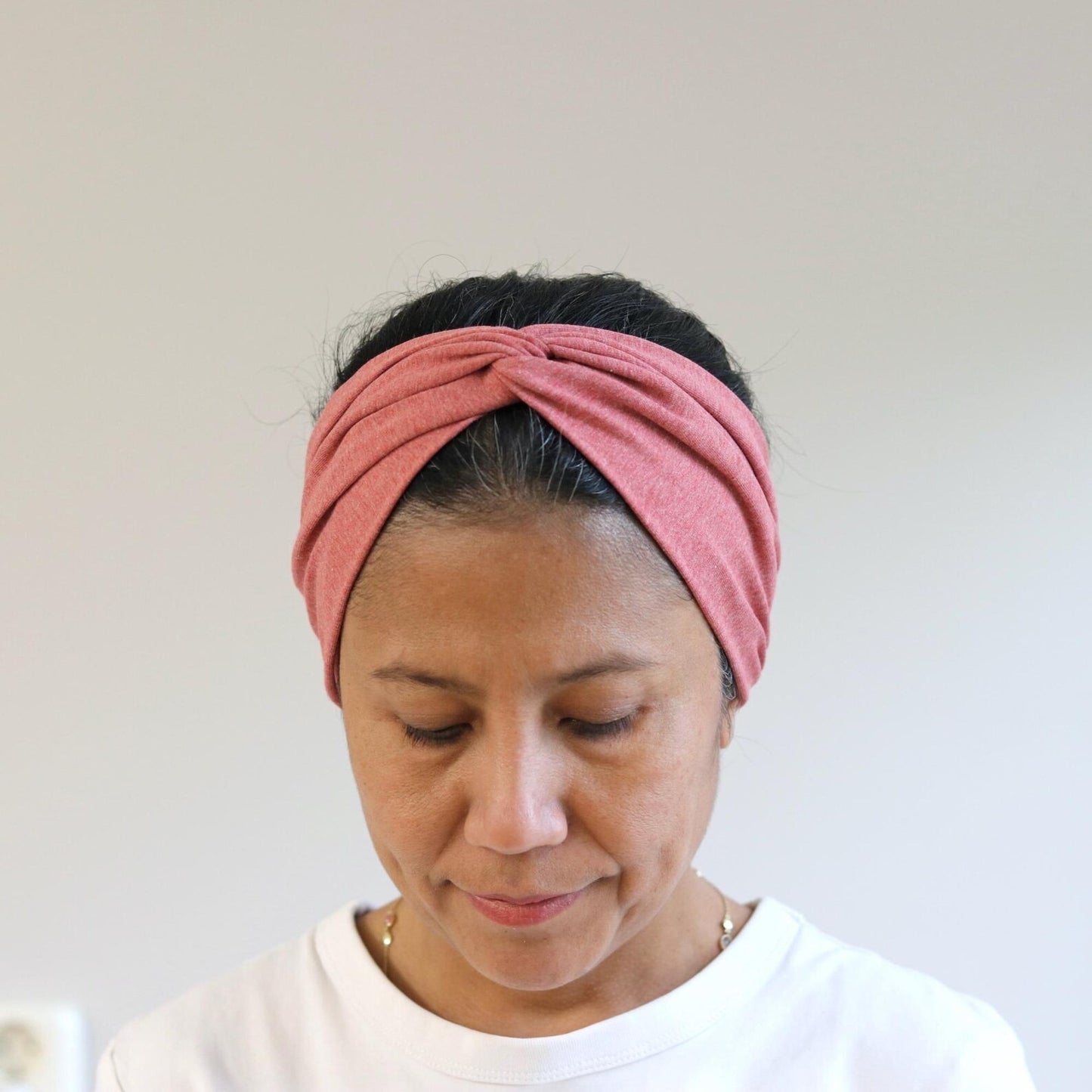 Woman wearing a red twisted headband against a plain background