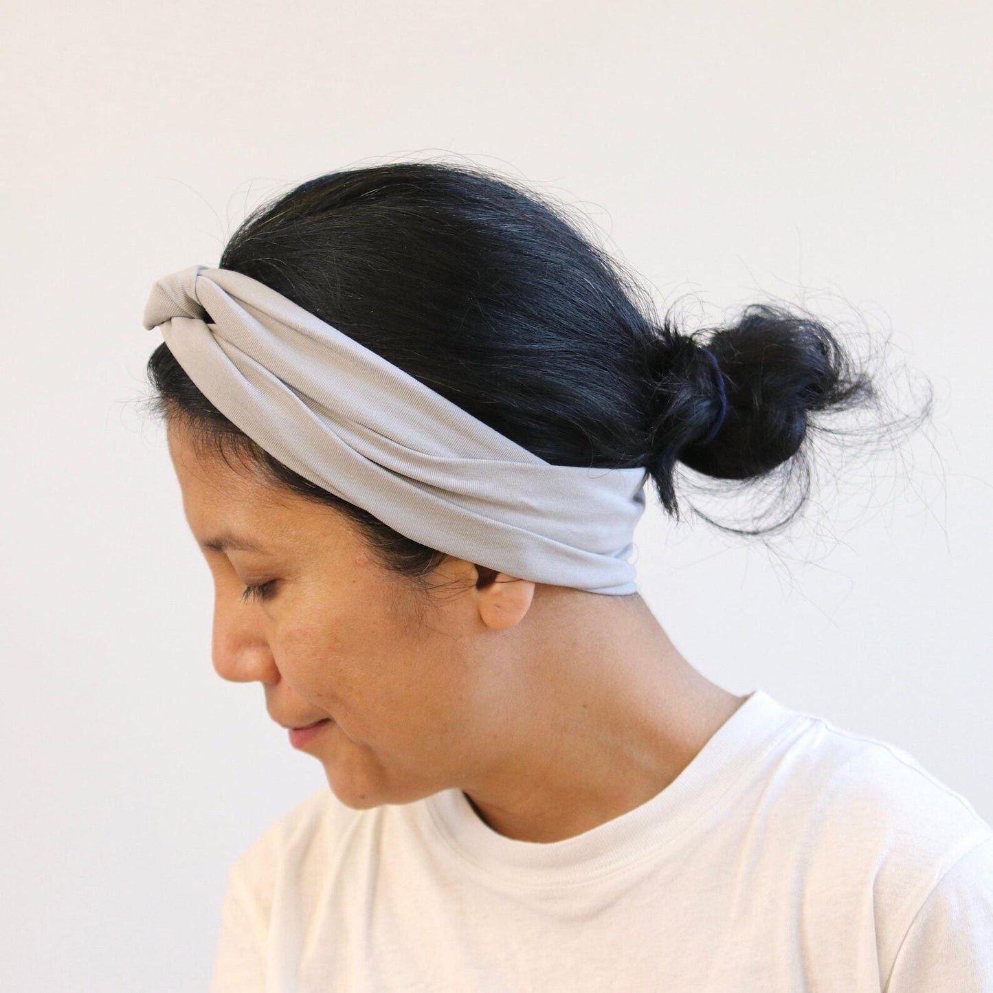 Woman wearing a light gray headband against a white background