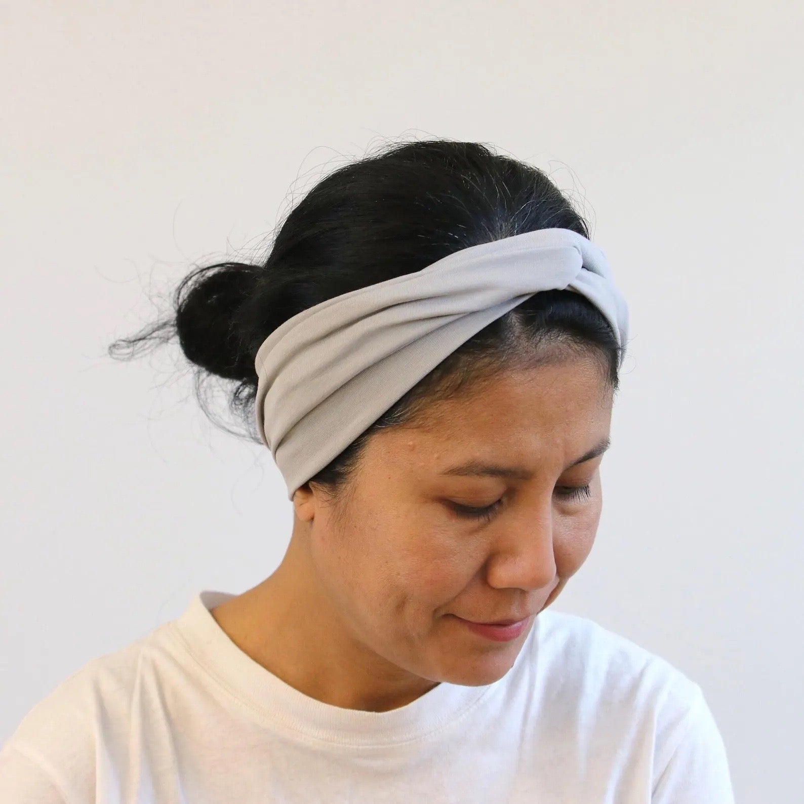 Woman wearing a light gray headband against a plain background
