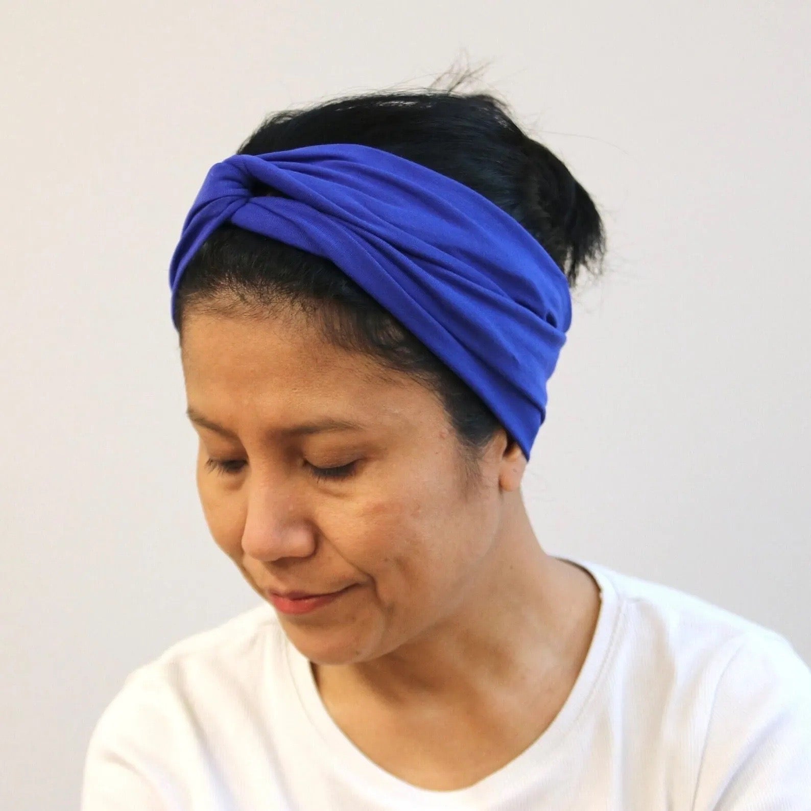 Woman wearing a blue headband against a plain background