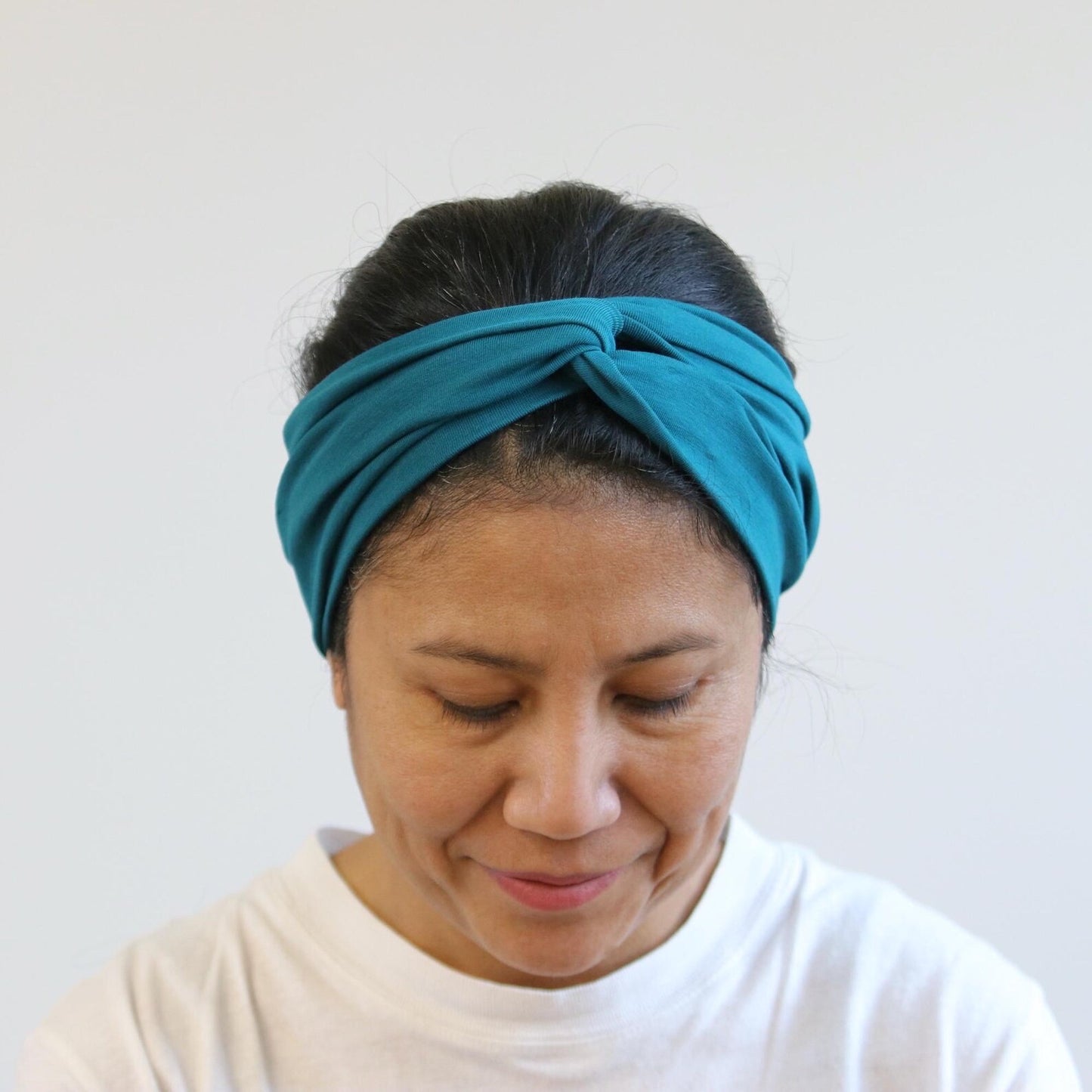 Woman wearing a teal headband against a white background